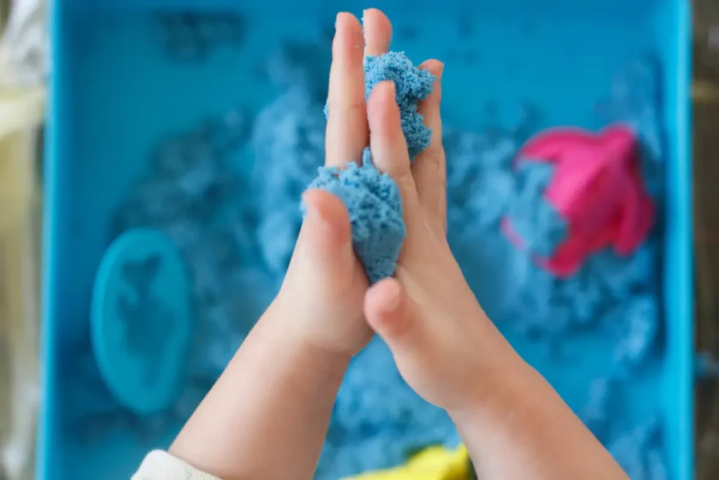 bawi się piaskiem kinetycznym leżącym w pudełku